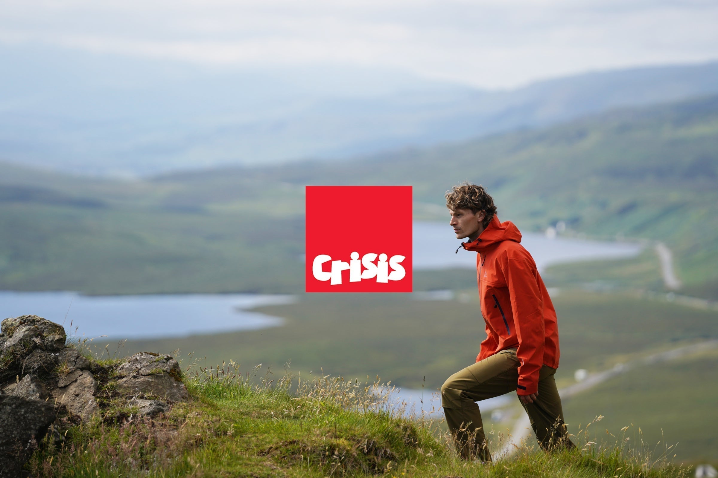 Man hiking in the hills wearing Fjern outdoor gear, with the Crisis UK logo displayed
