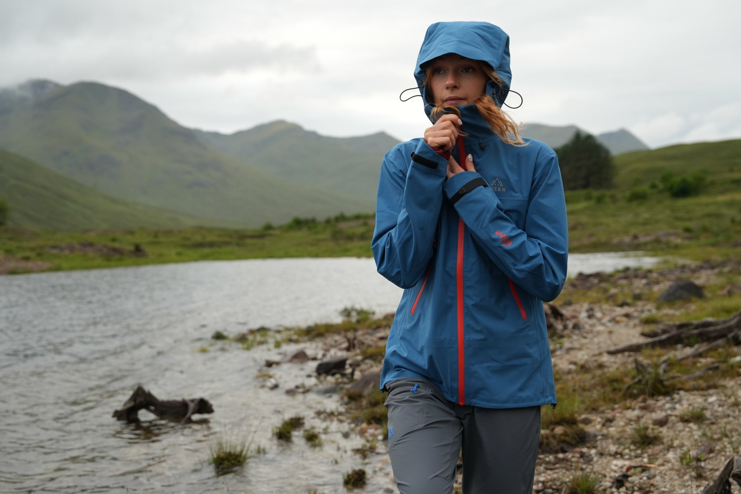 Person wearing waterproof jacket by mountain lake
