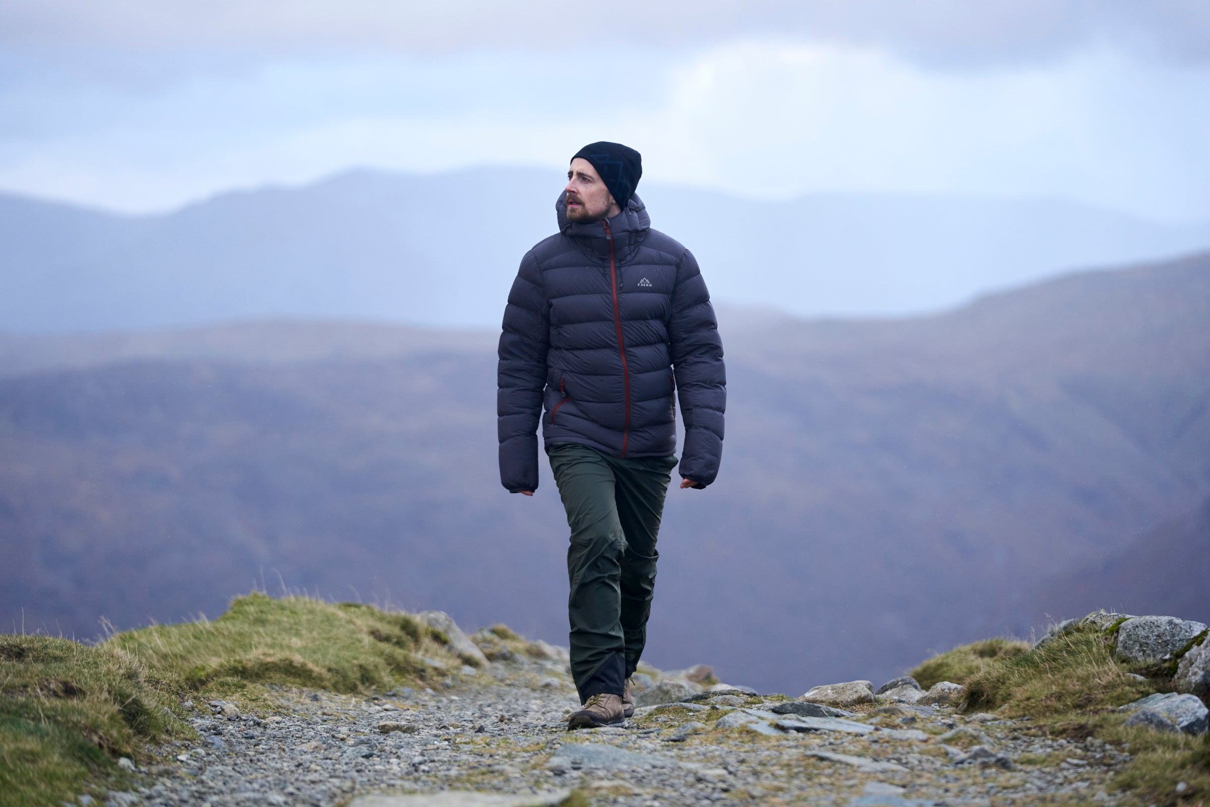 Person hiking on a mountain trail wearing a insulated jacket