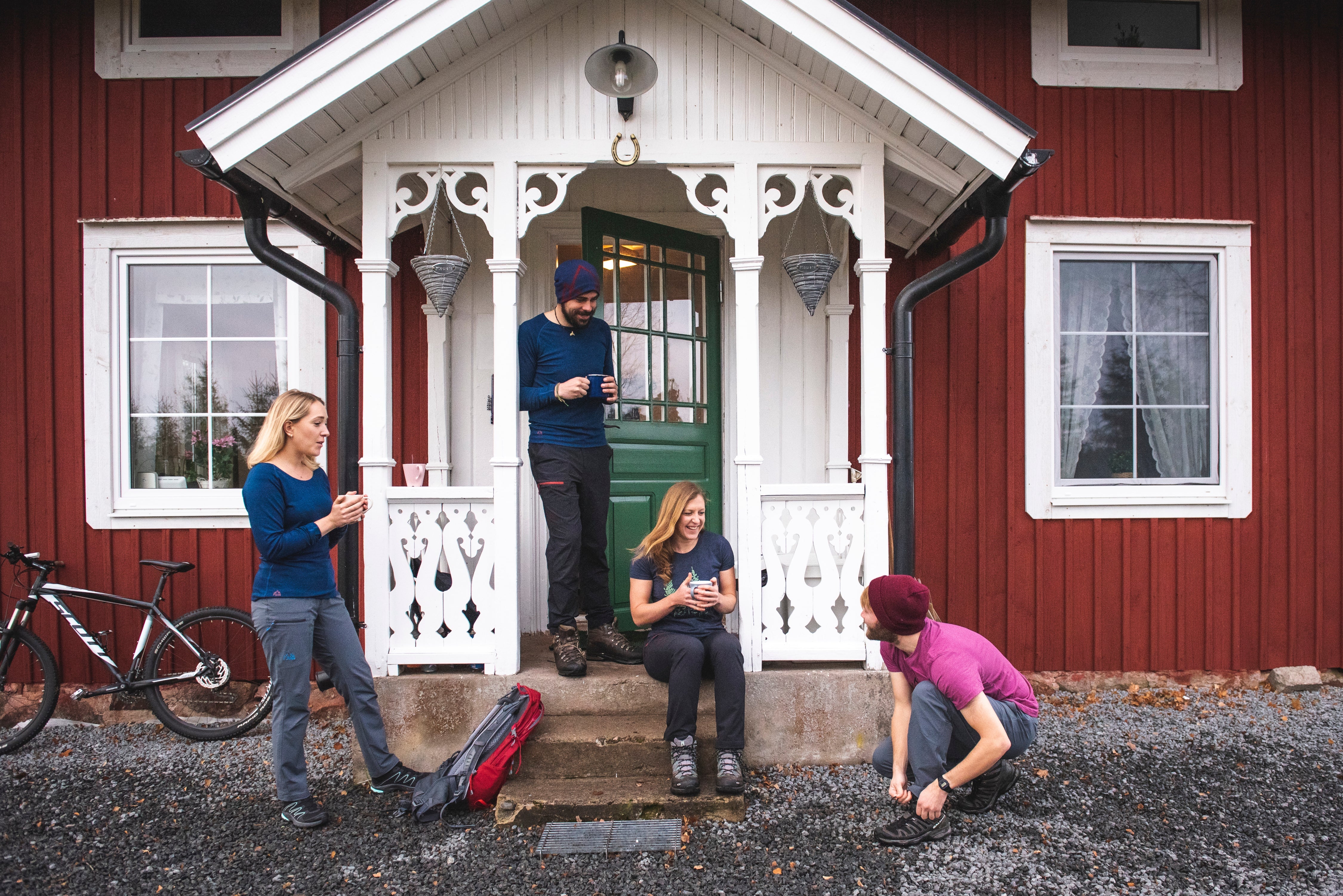 Collection of Fjern Base Layers and T-Shirts being worn on the porch of a wooden house in Finland