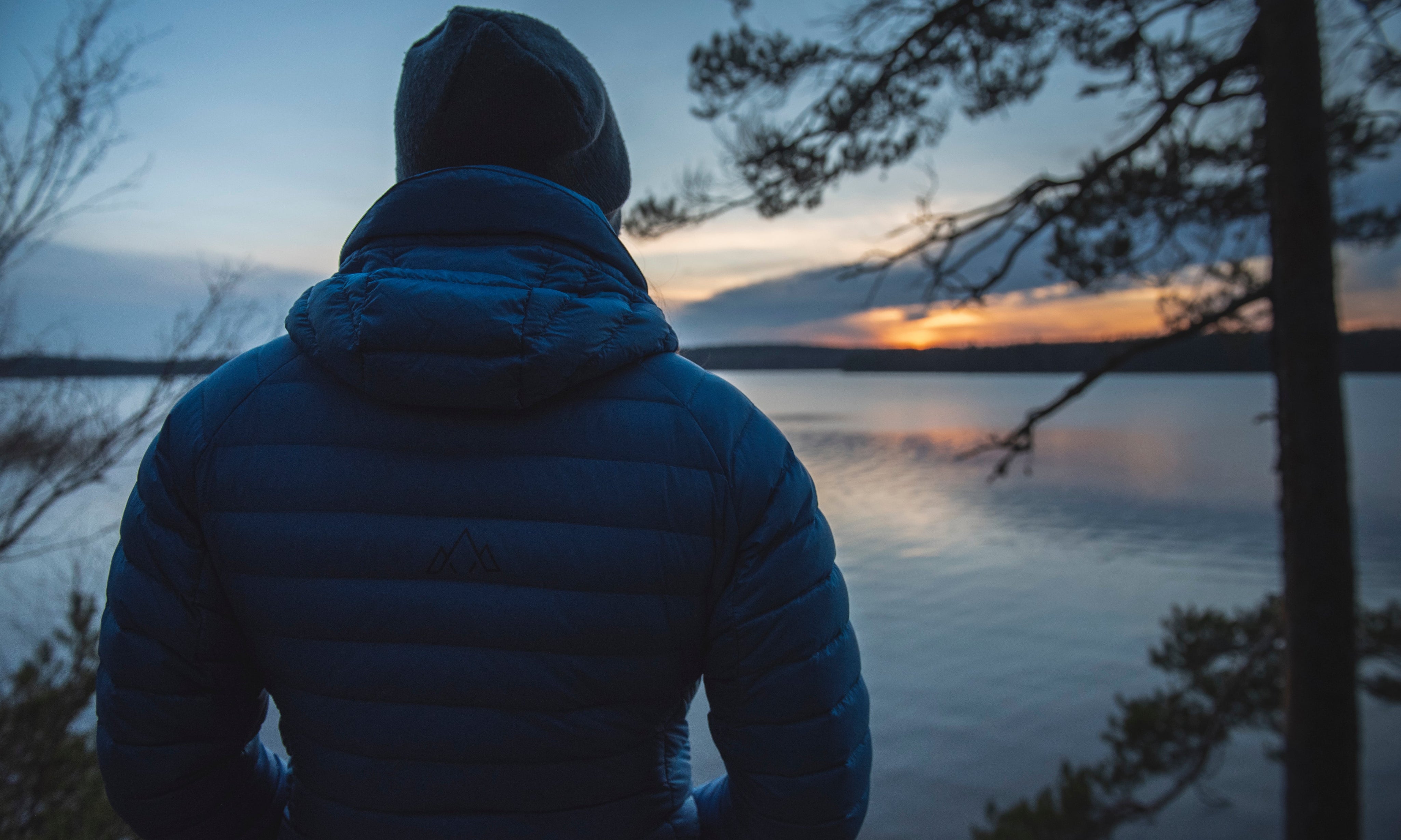 Rear shot of the Aktiv Jacket overlooking a vast lake at dusk