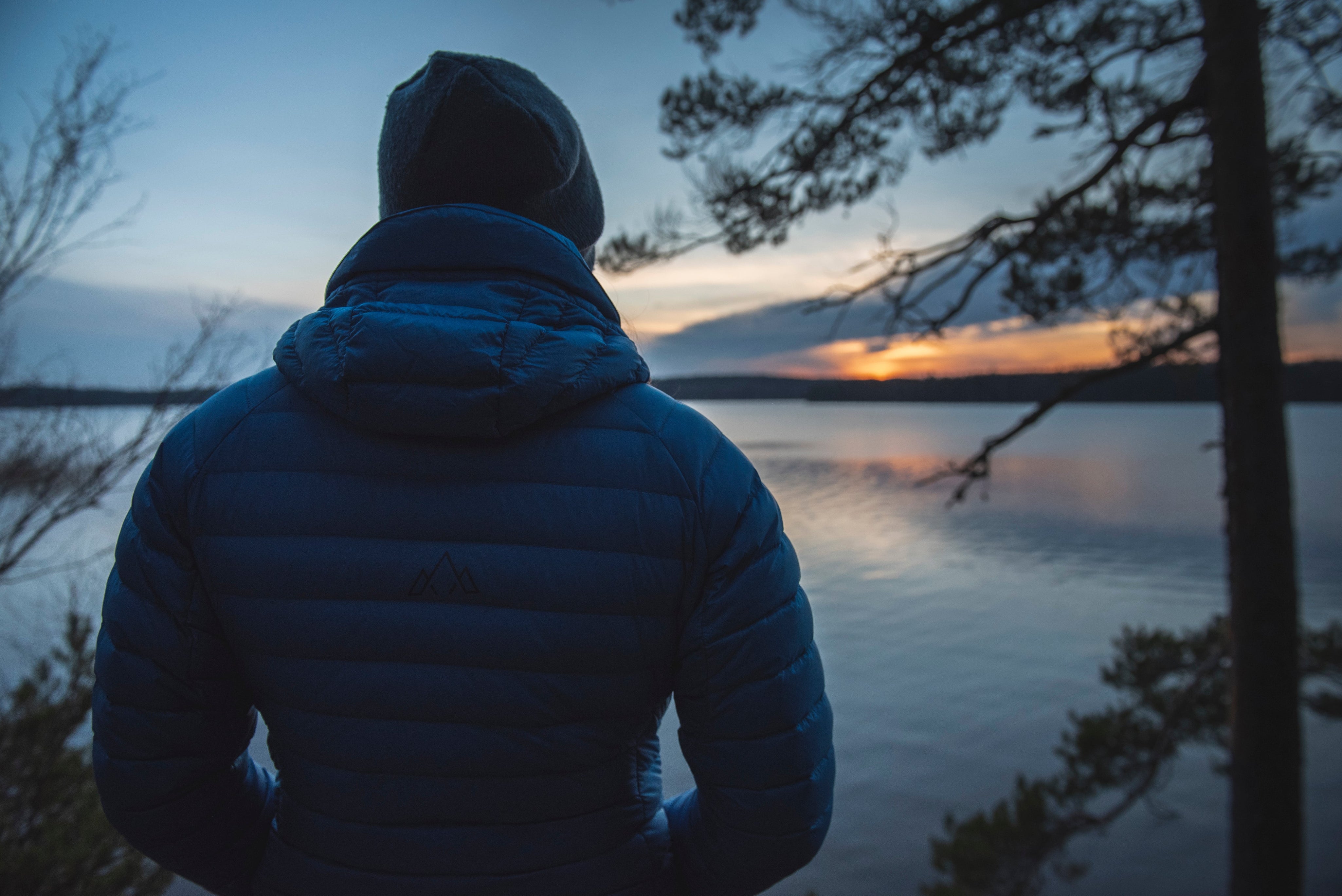 Rear shot of the Aktiv Jacket overlooking a vast lake at dusk