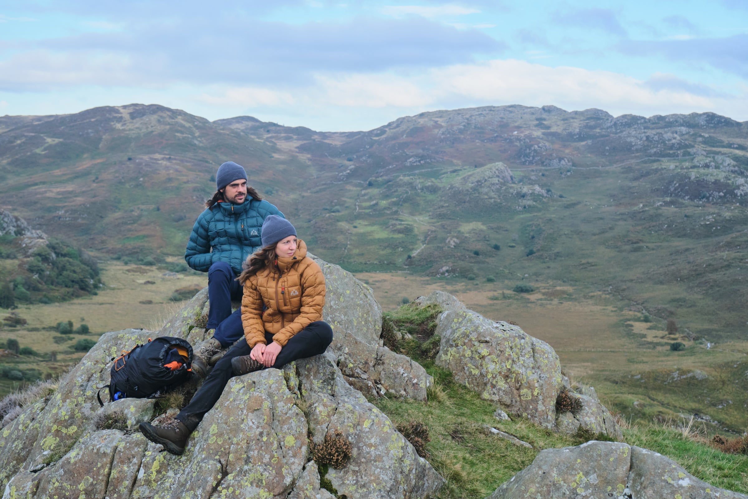 Fjern Eldur Jackets on a rocky rest stop in a vast hilly landscape
