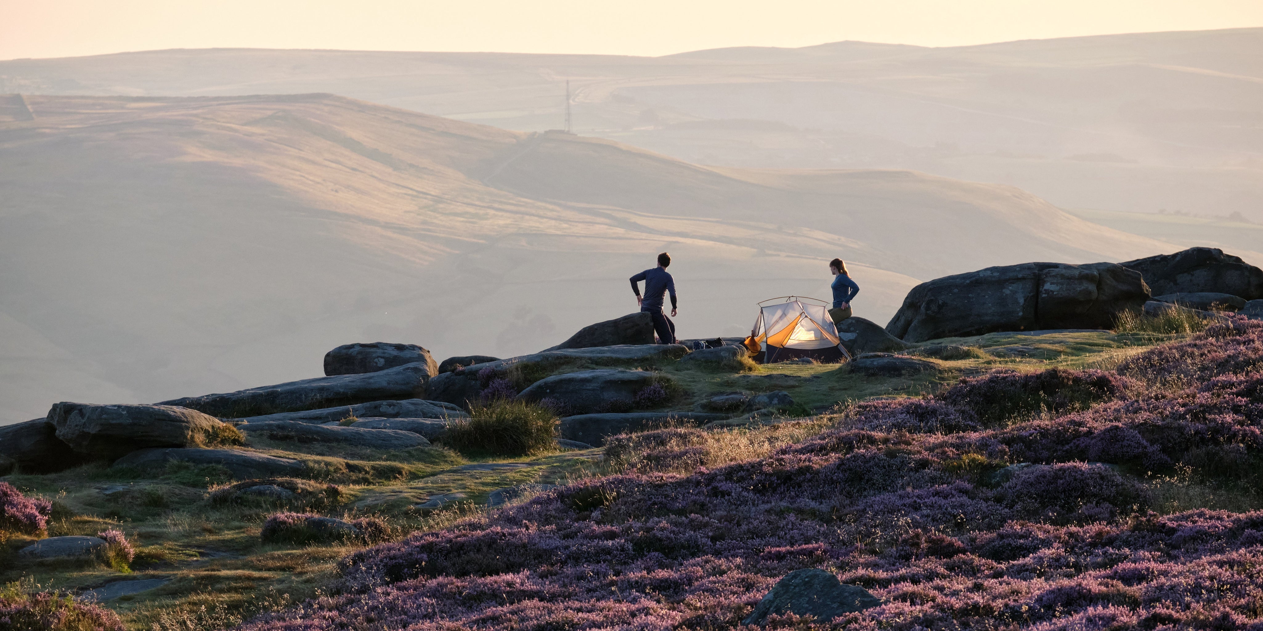 Wide shot of a tent pitched atop a hill in a valley of rolling hills