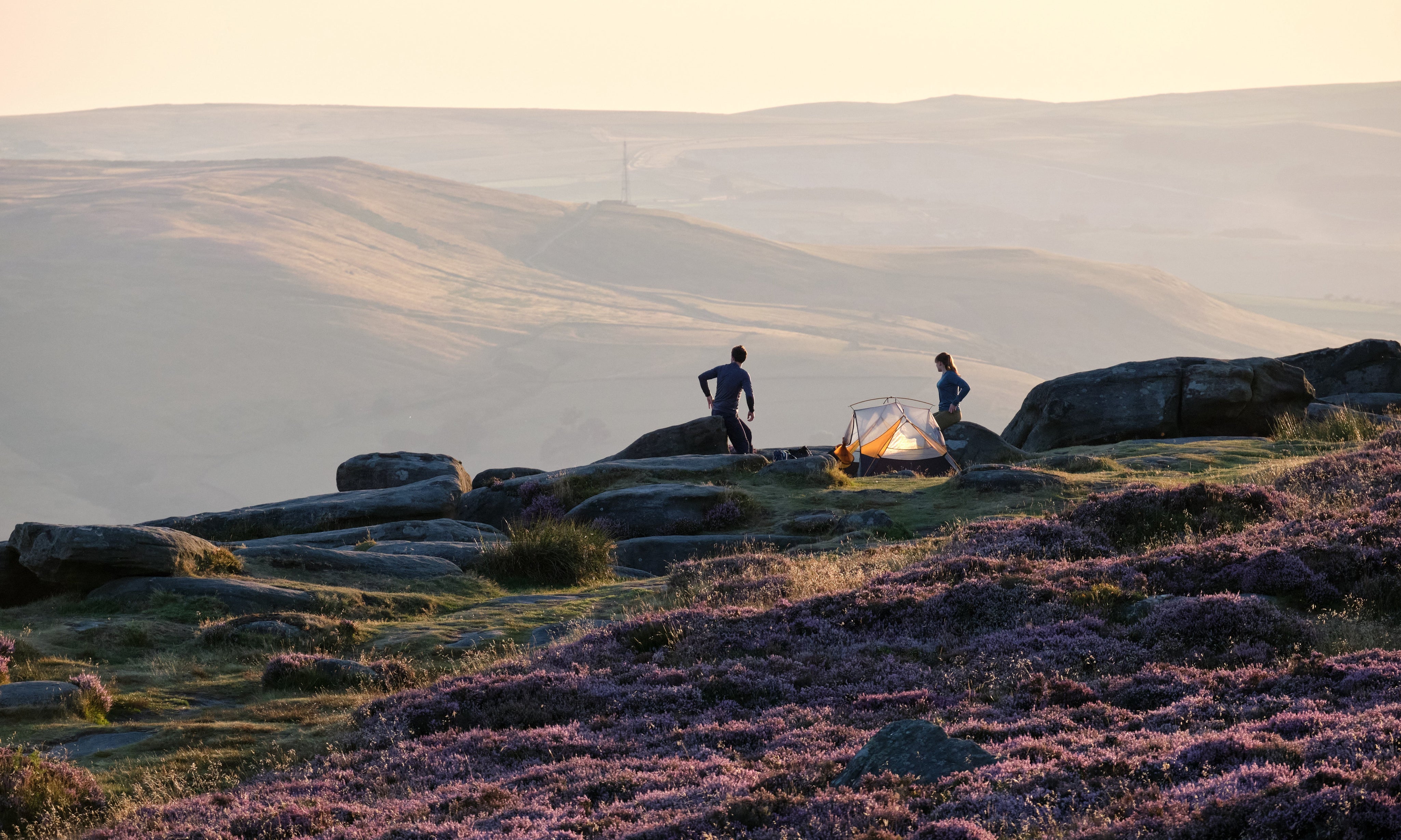 Wide shot of a tent pitched atop a hill in a valley of rolling hills