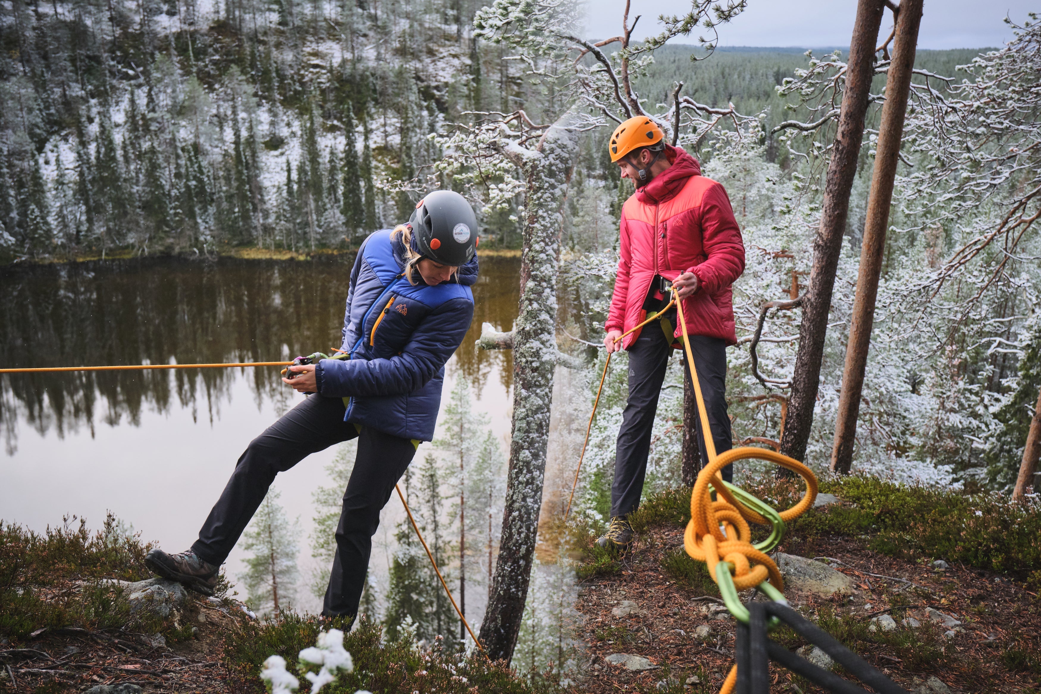 Fjern Husly Insulate Belay Jackets tackling a cliff decent in a snowy Finnish landscape