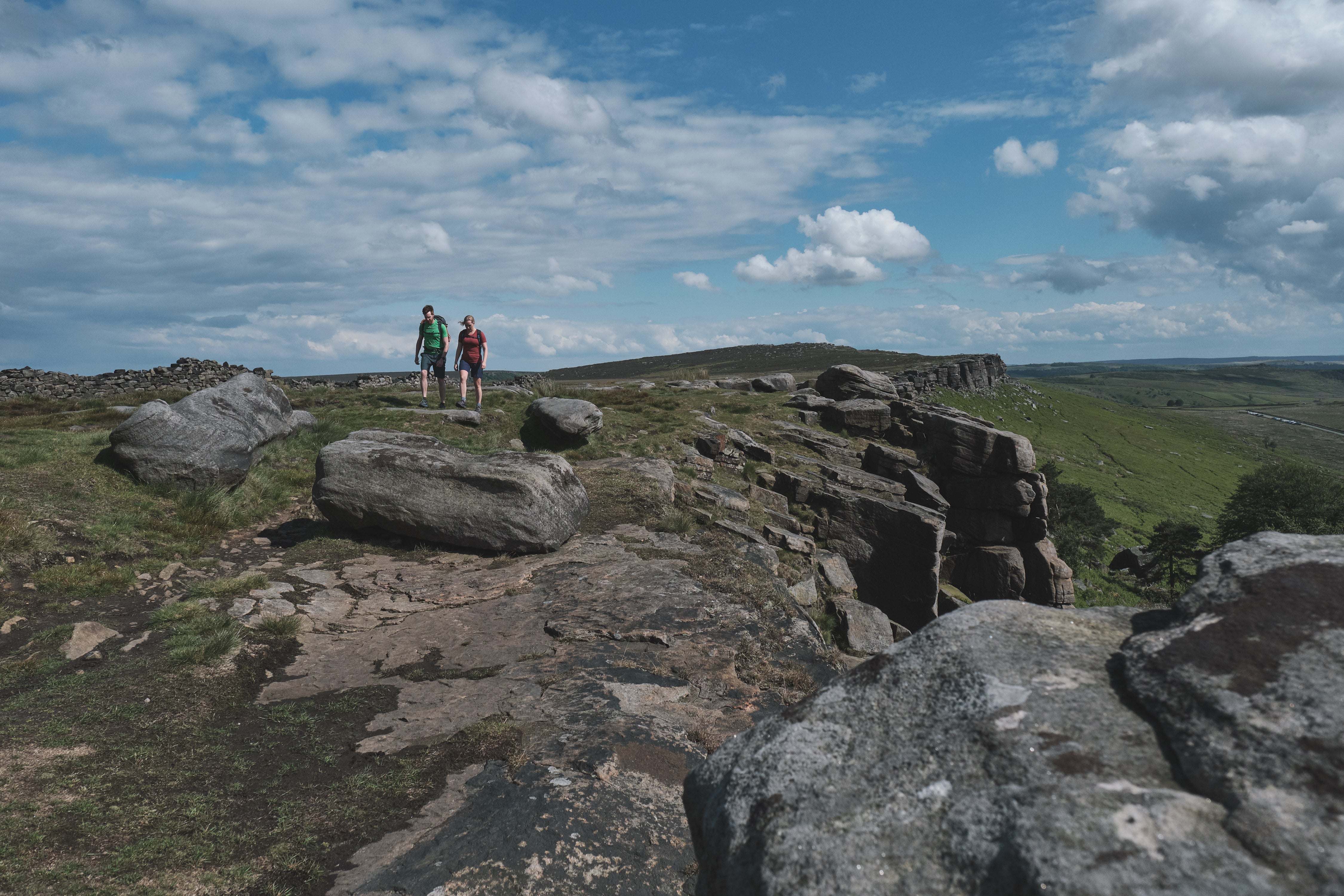 Wide shot of two hikers wearing Andas Crews on top of a sunny hillside