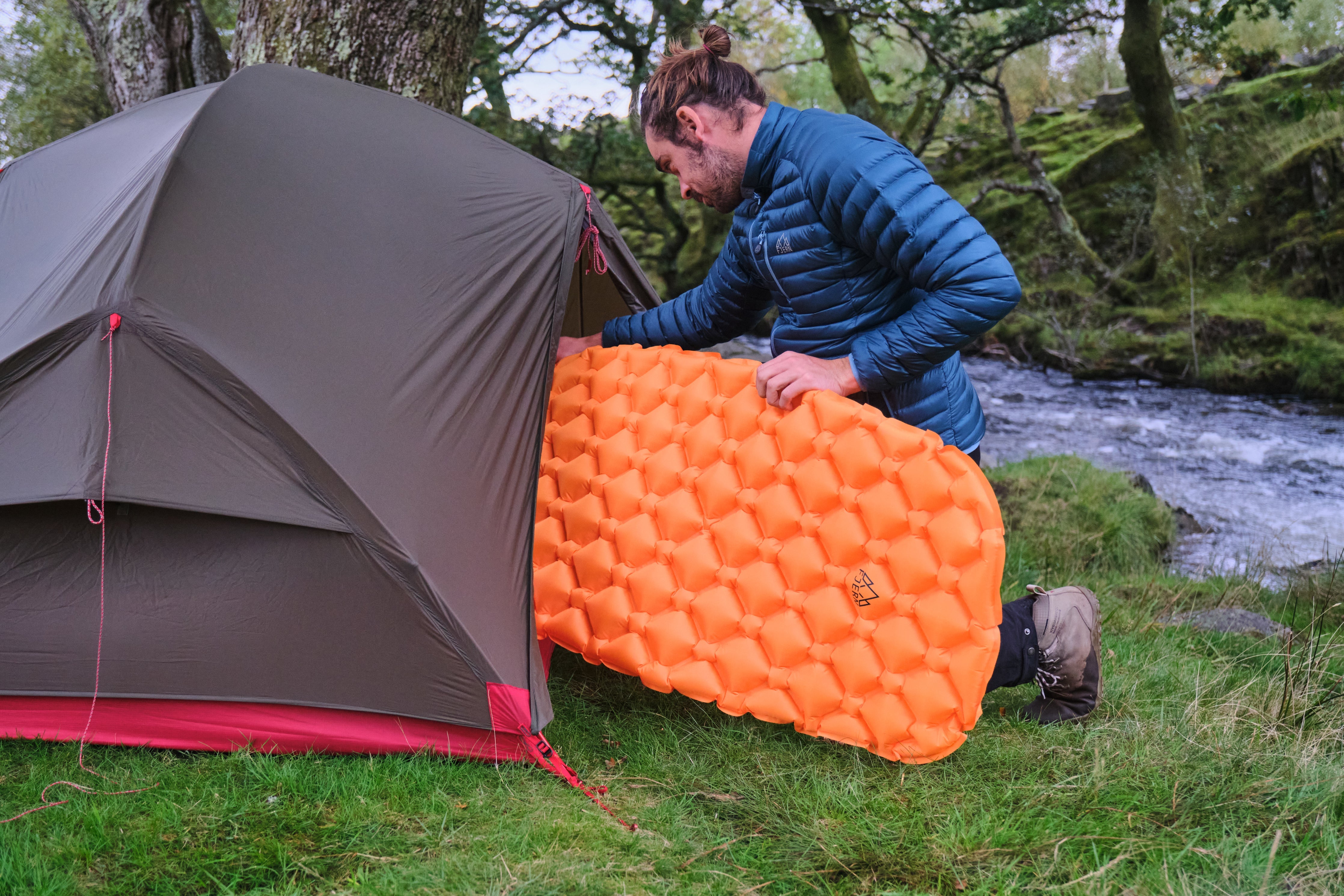 Fjern Snabb Camping Mat being carefully positioned inside a tent pitched next to a fast flowing stream