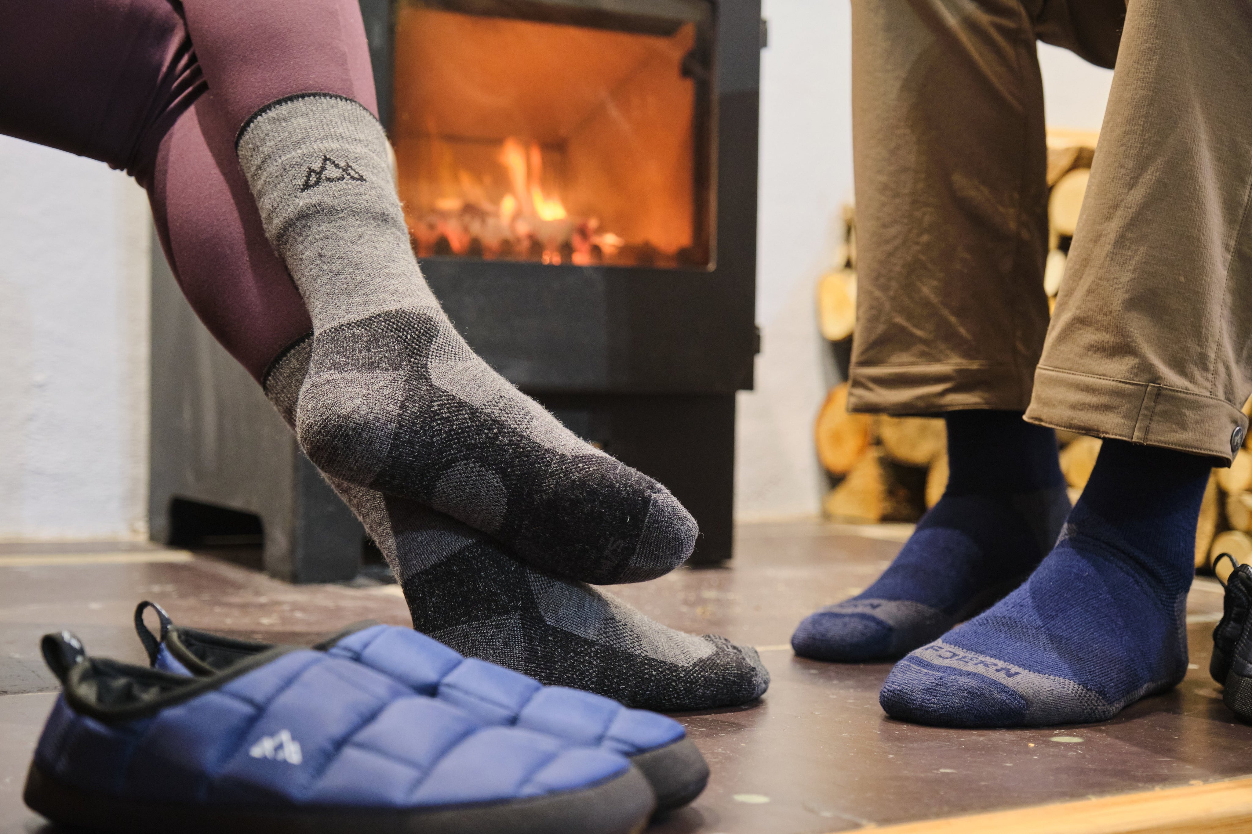 Fjern Tarn Hiking Socks and Tøffelhelt Tent Slippers next to a warm log burner fire