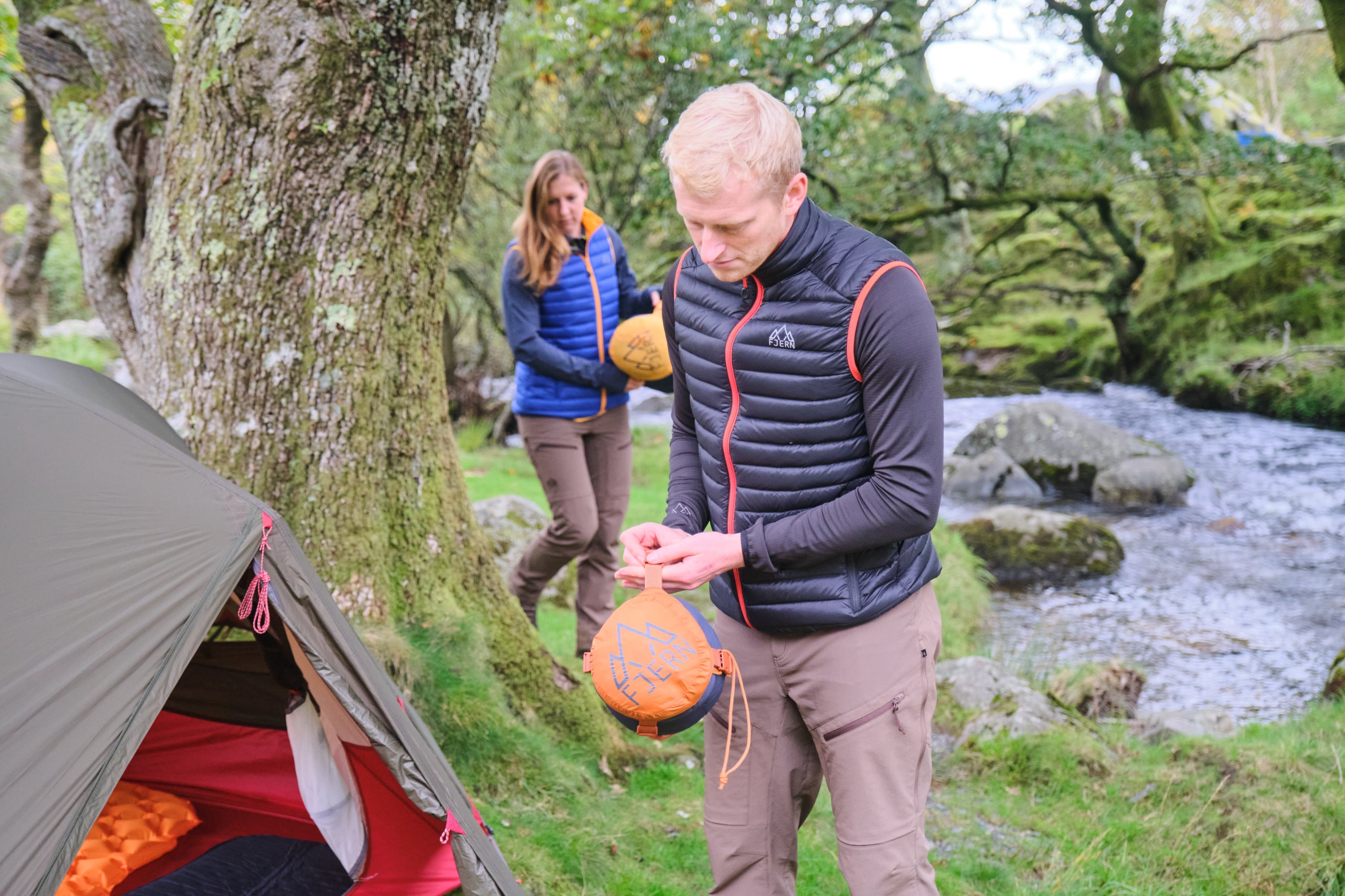 Aktiv Gilets worn during tent pitching by a forest creek