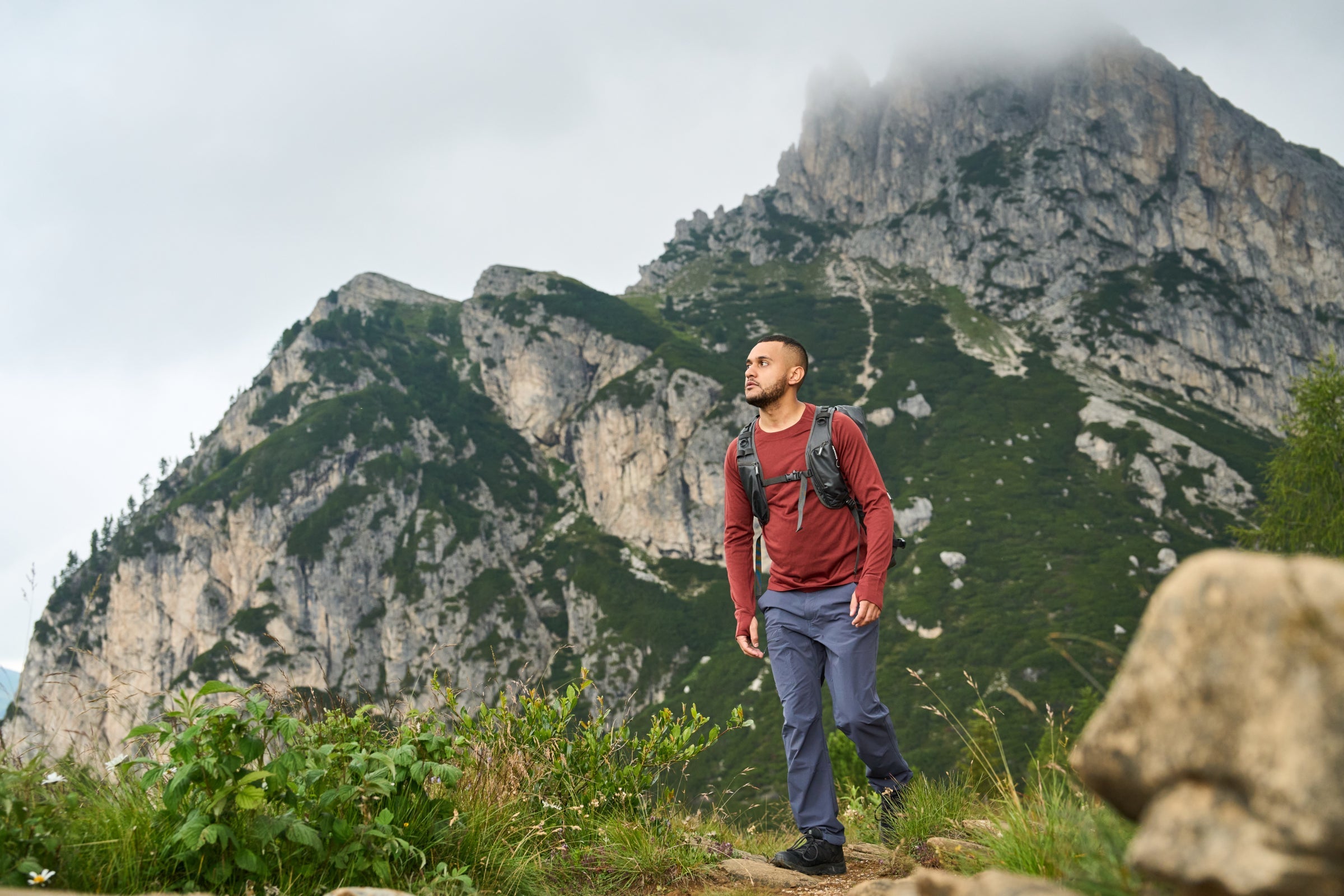Man hiking in mountains wearing Fjern long sleeve baselayer and backpack