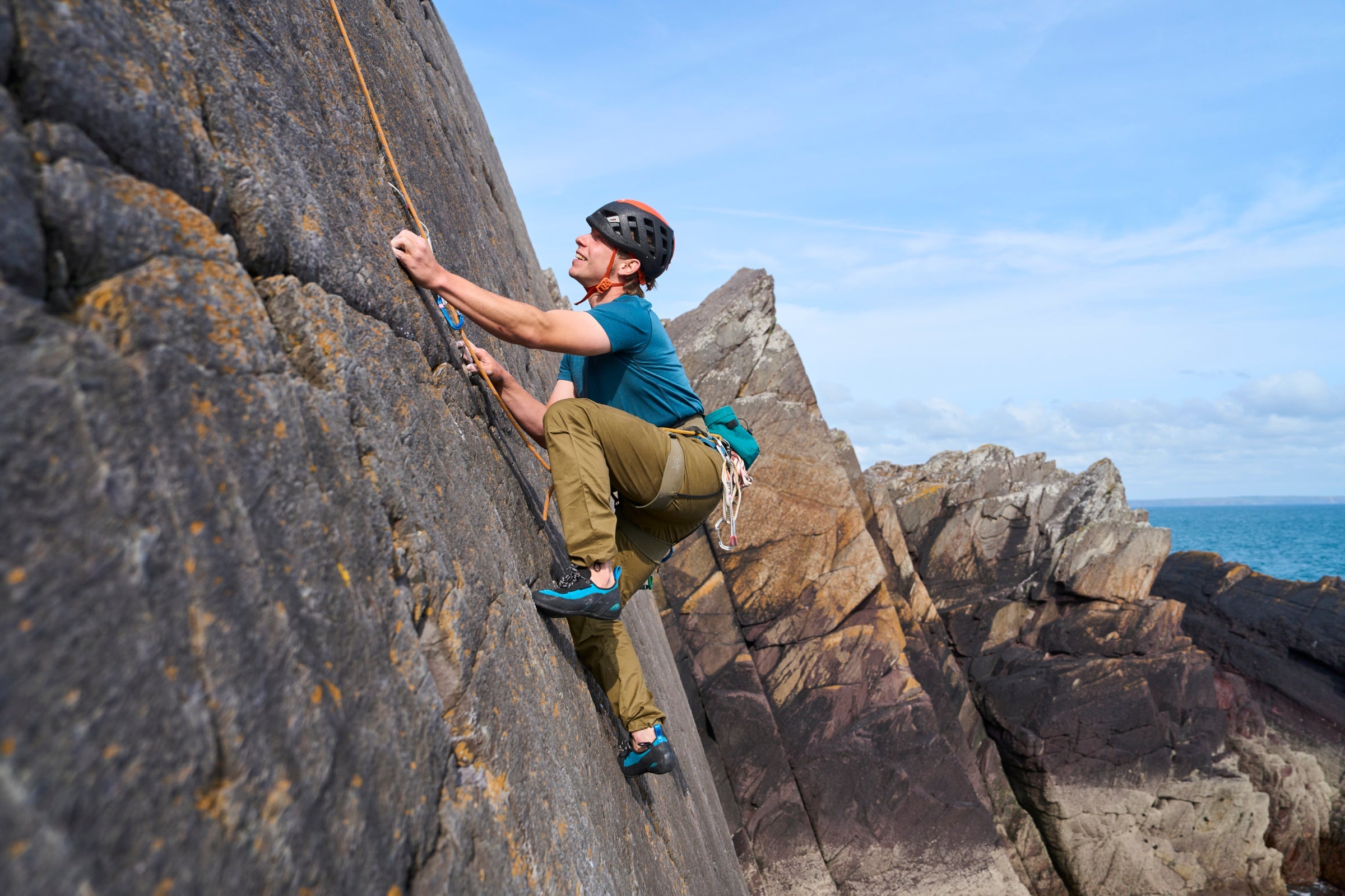 Man climbing outdoors in Fjern climbing trousers, using rope protection on a steep rock face