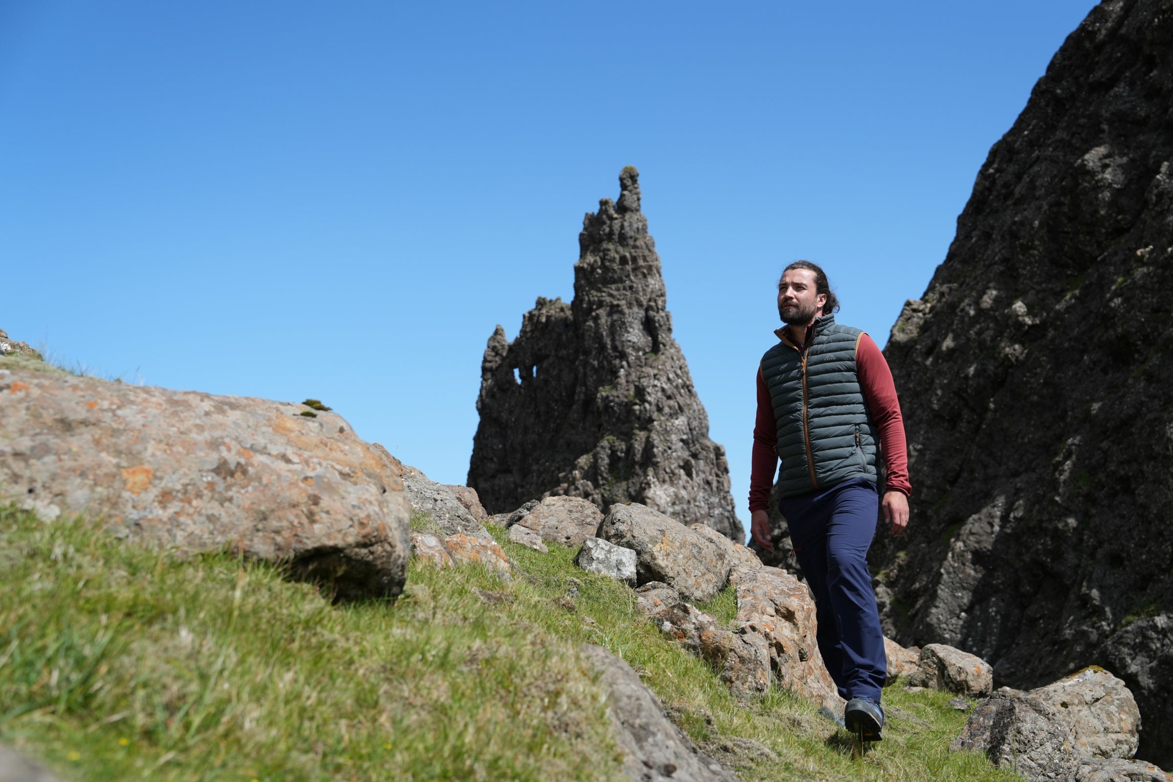 Man hiking in Fjern insulated gilet, walking through rocky mountain landscape