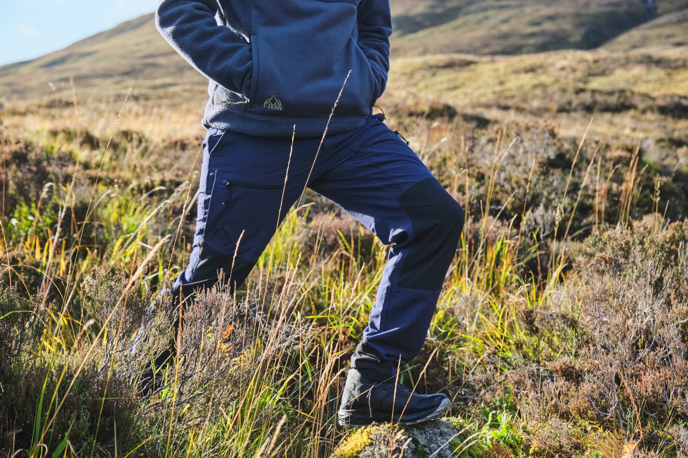 Man hiking through moorland wearing Fjern outdoor trousers and fleece