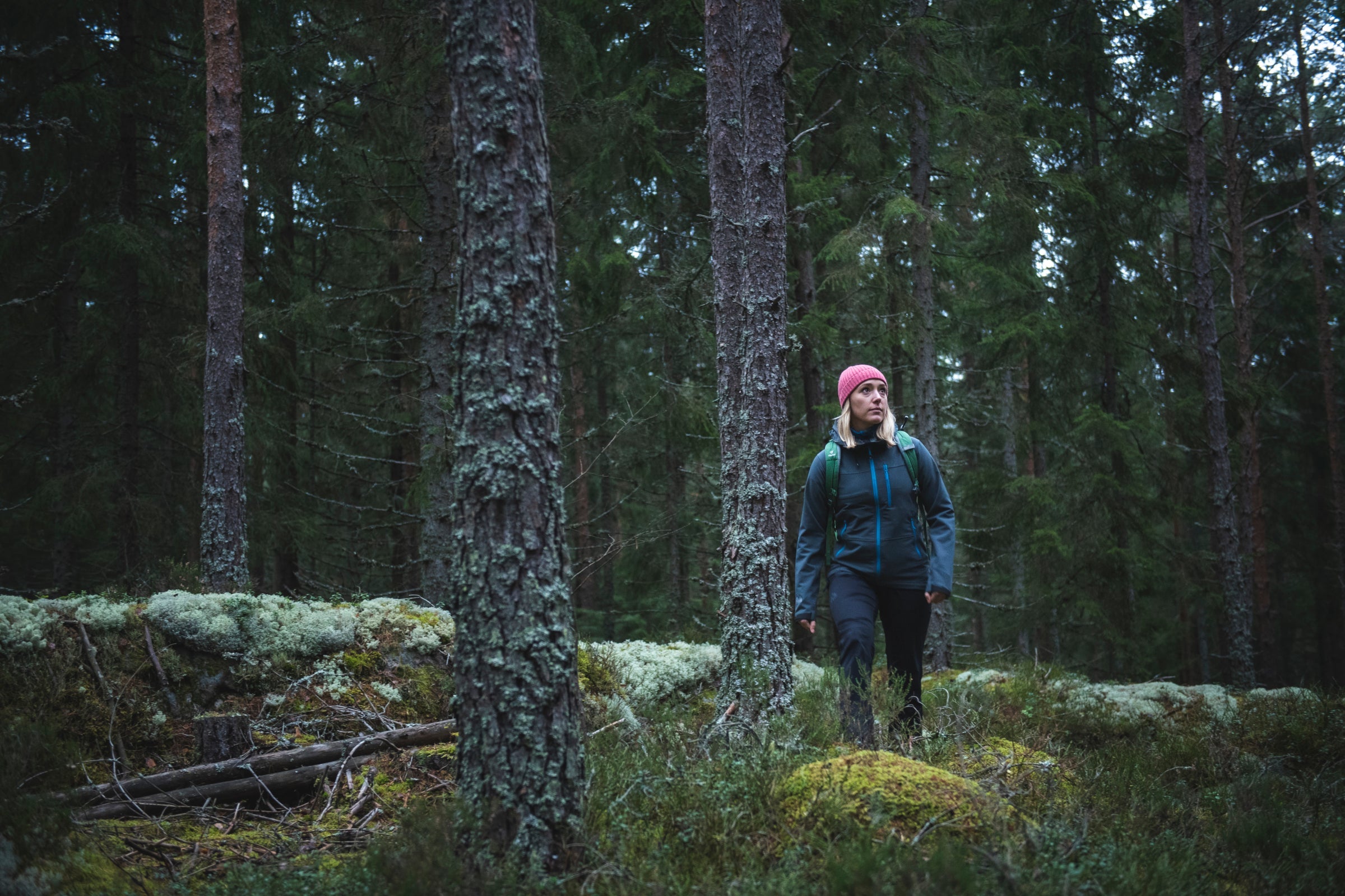 Woman hiking in forest wearing Fjern softshell jacket and backpack