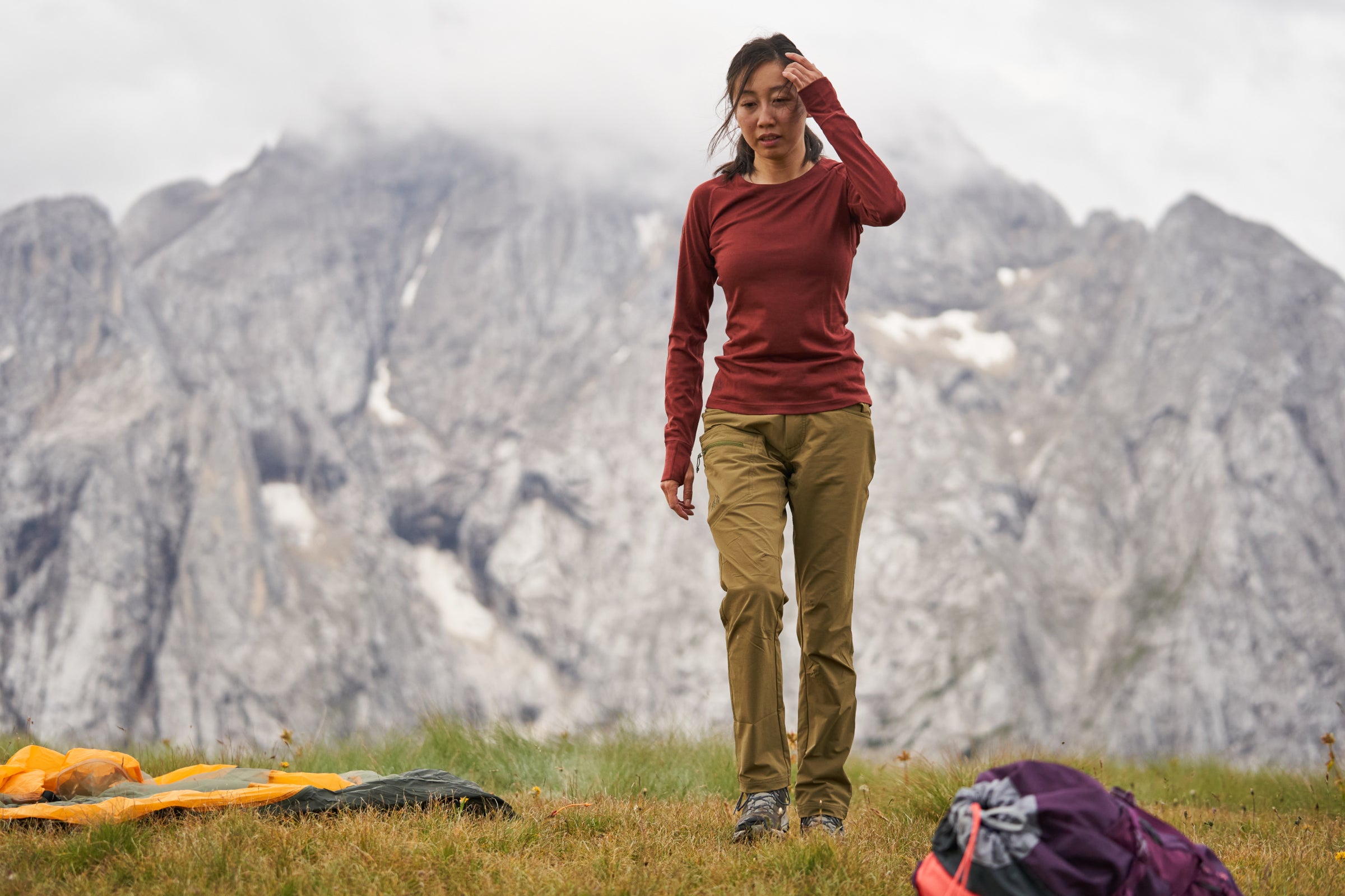 Person standing in a grassy area with mountains in the background