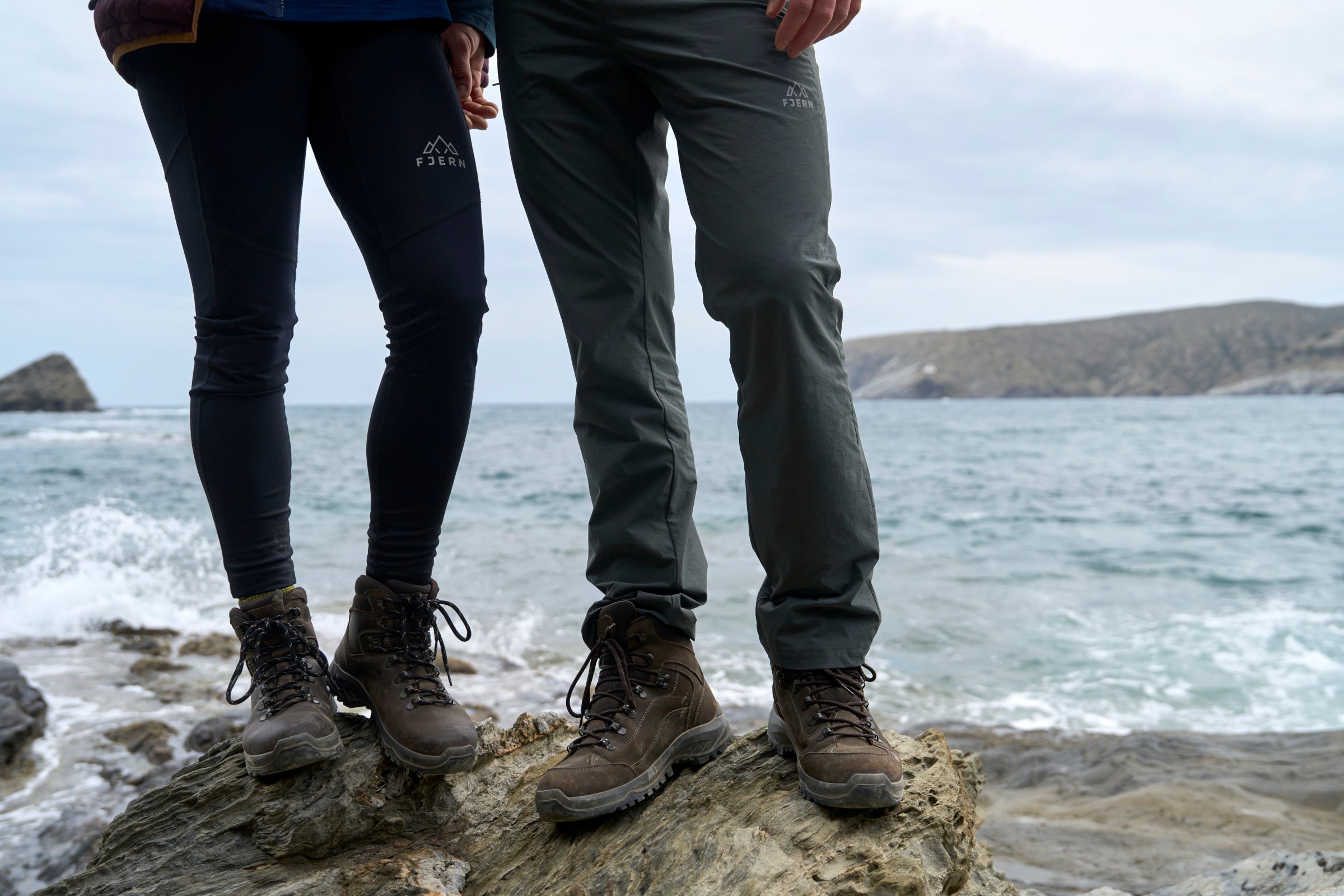 Two people standing on a rocky outcrop by the sea