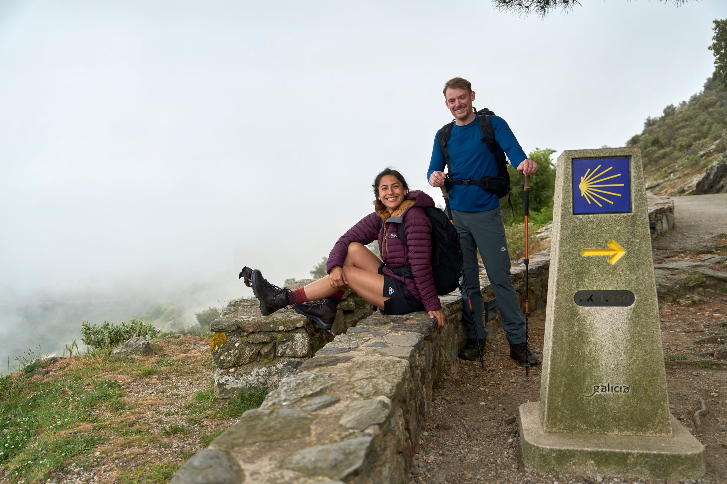 Two hikers taking a break on a misty mountain path