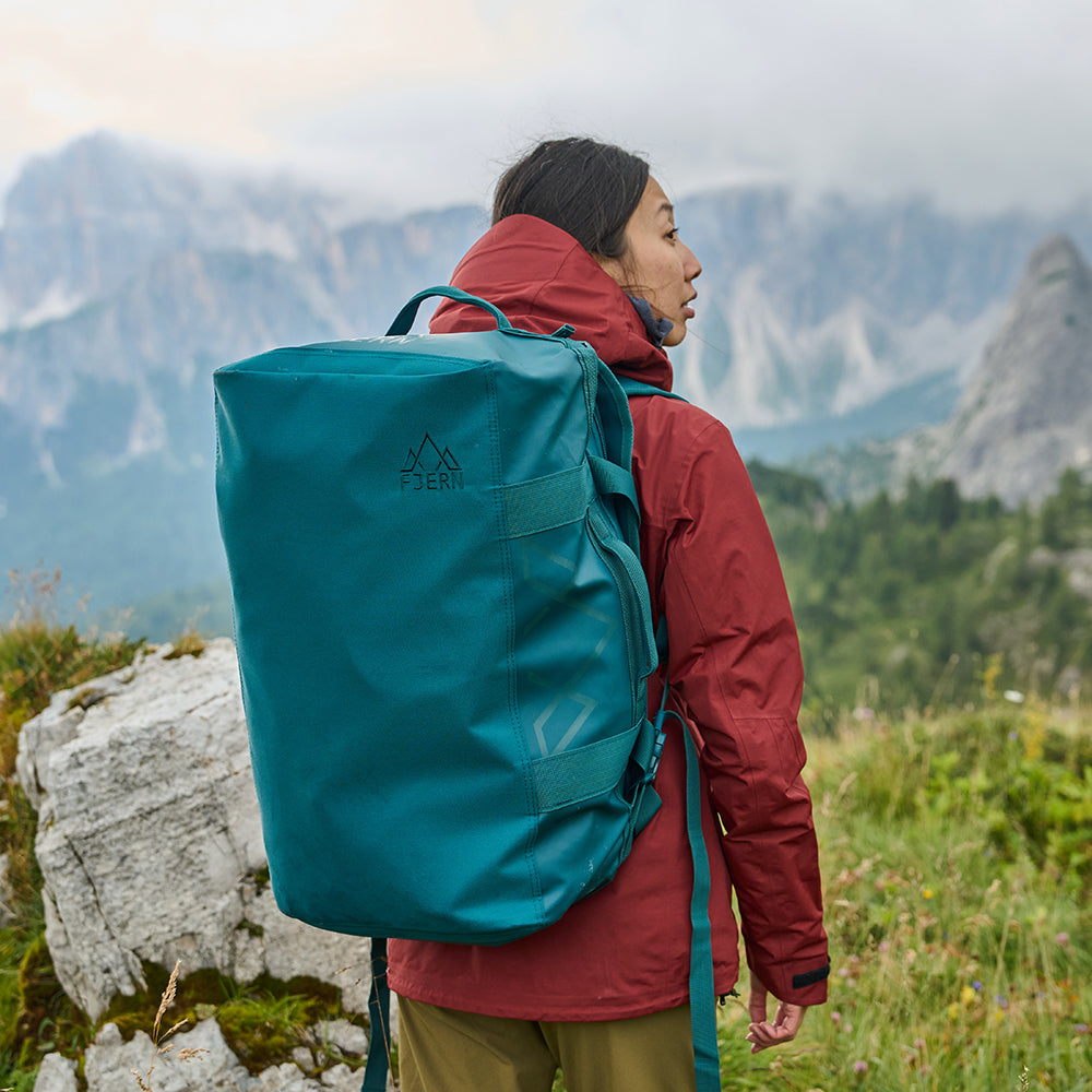 Fjern - Fördra 40L Duffle Bag (Petrol) | Made from durable 100% recycled polyester with a TPU-film laminate, the Fördra duffle bag offers 40L of storage, multiple pockets, and versatile carrying options