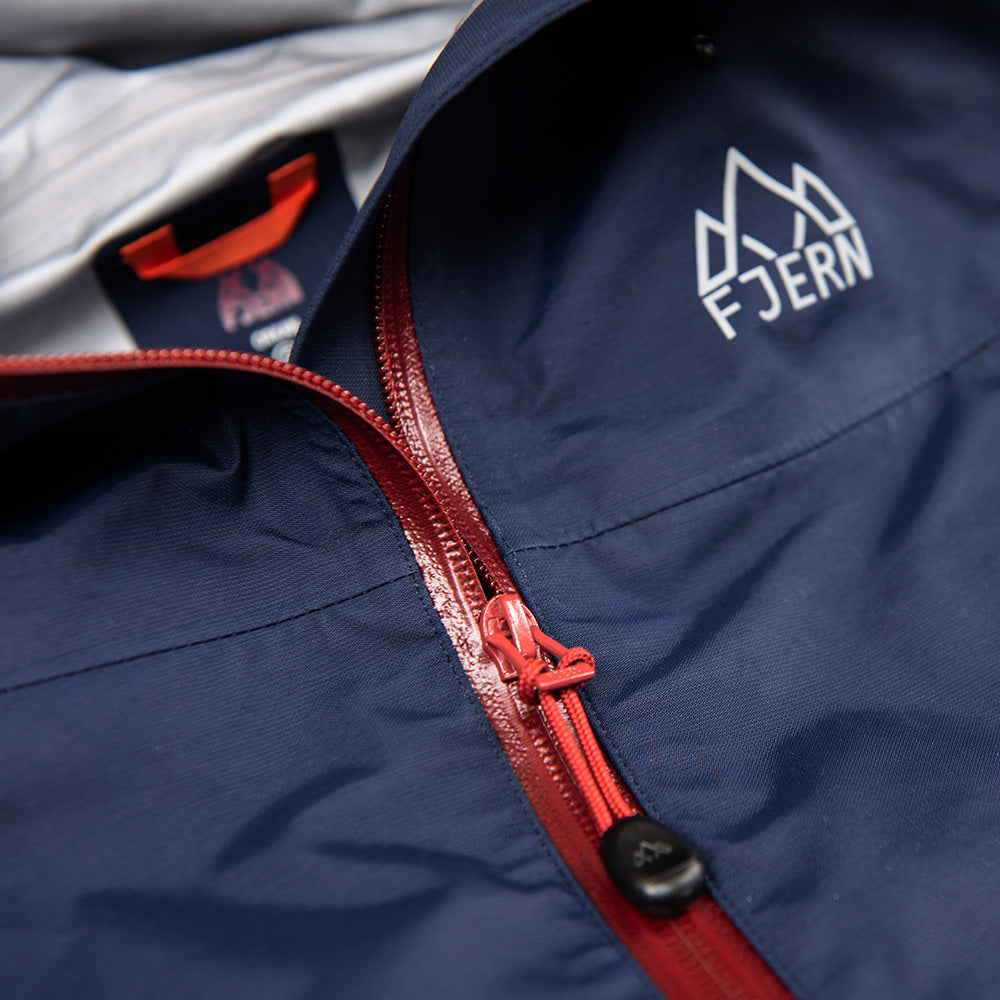 Fjern - Womens Orkan Waterproof Shell Jacket (Navy/Rust) | Face the harshest alpine challenges with confidence in the Orkan jacket, engineered to excel in extreme conditions